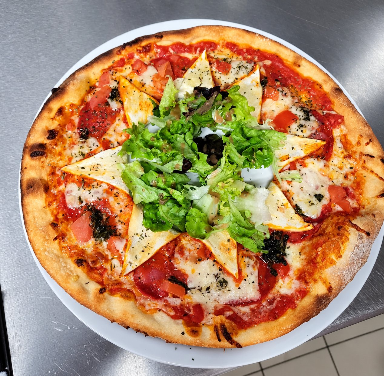 Pizza à la croûte dorée, nappée de sauce tomate, de fromage fondu et d'herbes, avec une salade verte au centre, posée sur une assiette blanche.